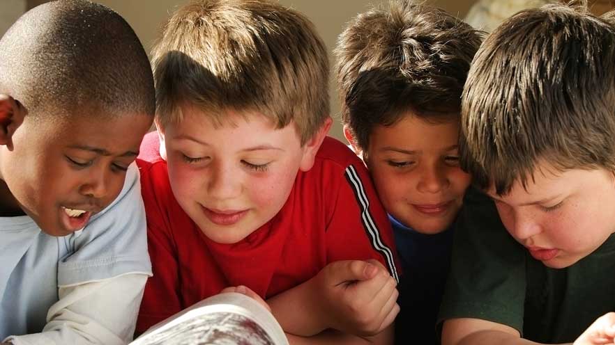 A group of boys reading a book.